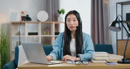 Woman Works at Laptop, Wears Headset at Home