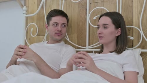 Attraktives junges Paar sitzt im Bett und spricht