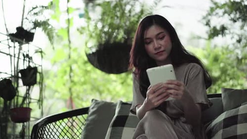 Woman Using Tablet Relaxing on Outdoor Sofa