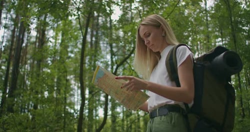 Young Caucasian Woman Looking for Direction on a Map While Hiking in the Forest. Happy Girl While