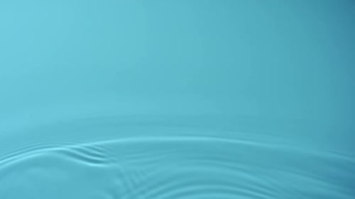 Slo-motion water rippling against blue background