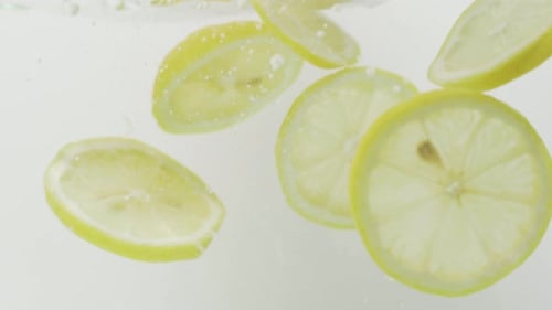Thin Slices Of Lemon Falls Into Water. - close up, studio shot