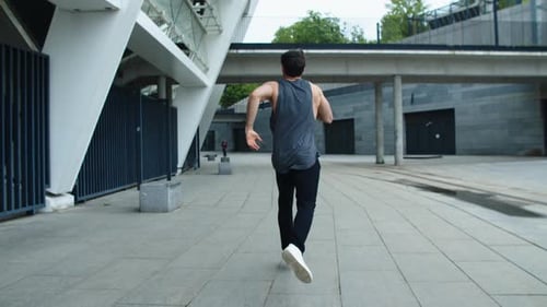 Back View of Sporty Man Running on Urban Street. Athlete Man Jogging Outdoor.