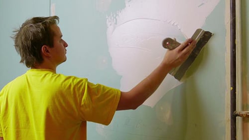 Young Adult Applying Spackle to an Interior Wall