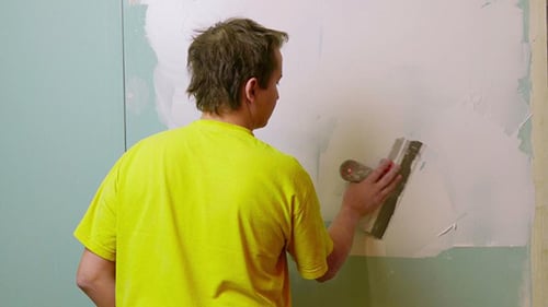 Man Applying Plaster to Wall Indoors