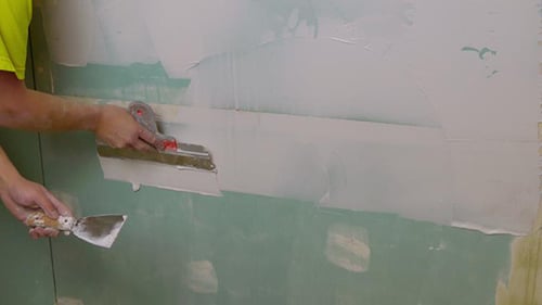 Adult Applies Joint Compound to Plasterboard Wall