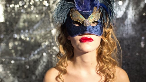 Woman Wearing Elaborate Mask with Glitter Background