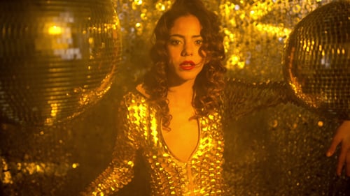 Glamorous Woman Dancing in Gold Sequined Jumpsuit