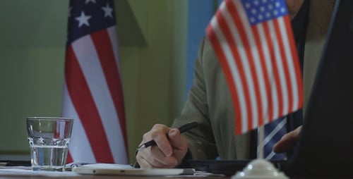 Man Working Hard at Desk with US Flags