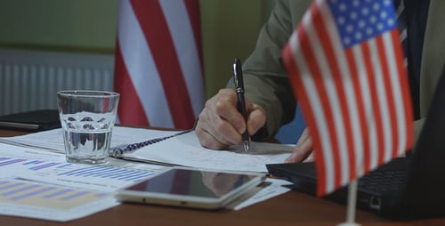 Man Writing at Desk with American Flag