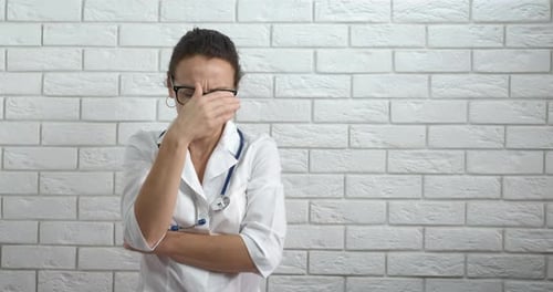 Frustrated Doctor in Distress against Brick Wall