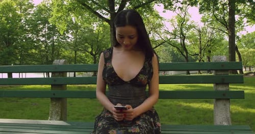 Chica enviando mensajes de texto en el teléfono celular en el parque b