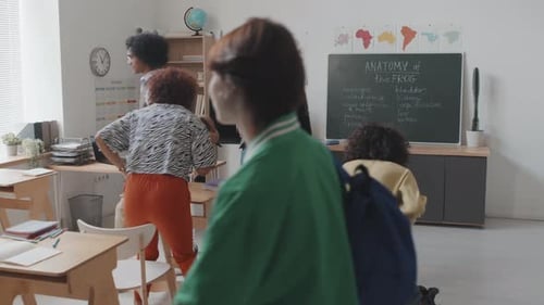Students Arriving and Teacher Distributing Papers in Classroom