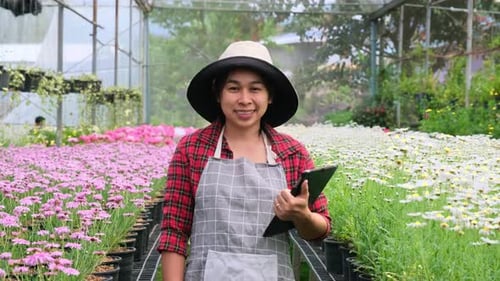 Smiling Gardener Among Colorful Flowers Holding Tablet