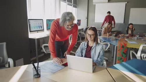 Senior Manager Helping Young Female Worker in Office