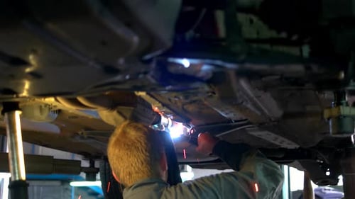 Mechanic Welding Under Car on Lift