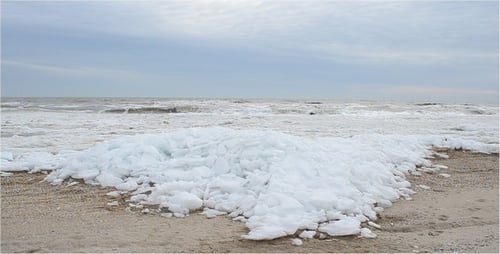 Icy Beach with Ocean Waves Crashing Shore