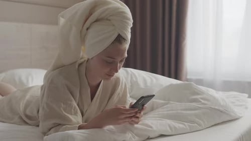 Woman Using Smartphone in Bed After Shower