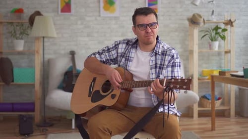 Young Man Musician with Glasses Can Not Play Guitar