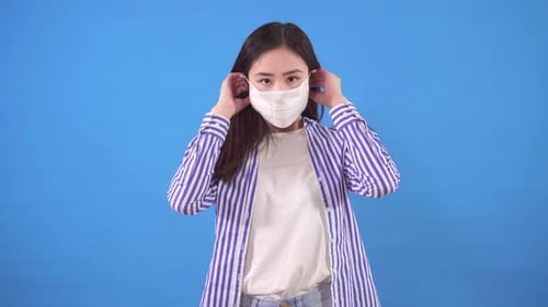 Young Woman Puts on Protective Surgical Mask