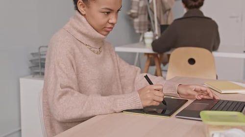 Woman Using Graphic Tablet and Laptop in Office