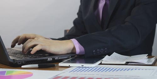 Professional Types on Laptop and Writes in Notebook