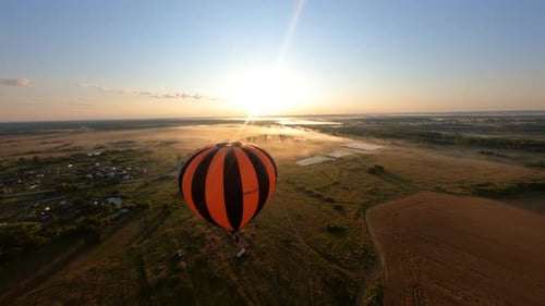 Hot Air Balloon Drifting in Rural Landscape at Sunrise