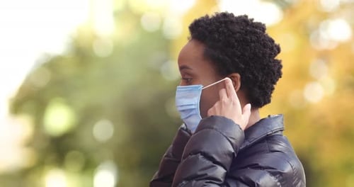 Woman Putting on Face Mask Outside