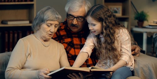 Grandparents Reading Photo Album With Grandchild At Home
