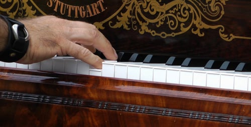 Man Plays Ornate Piano in Close Up