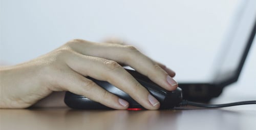 Hand operating computer mouse on desk close up