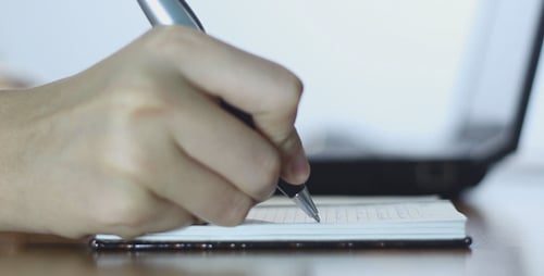 Woman Typing on Laptop and Making Notes