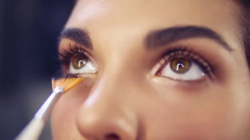 Maquilleur professionnel appliquant du fard à paupières sur le modèle des yeux à l'aide d'un pinceau spécial