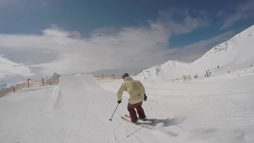 Ein junger Mann, der beim Skifahren und Abfahren fährt, springt in einem Geländepark auf einem schneebedeckten Berg.