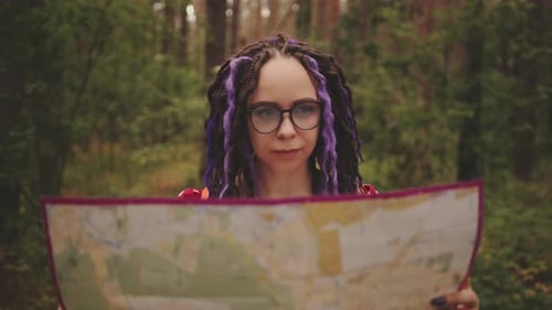 Traveling Woman with Dreadlocks with Map in Woods