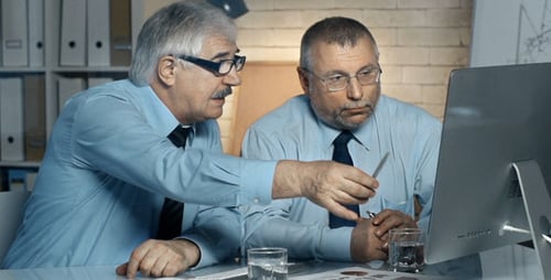 Businessmen Discussing Computer Screen in Bright Office