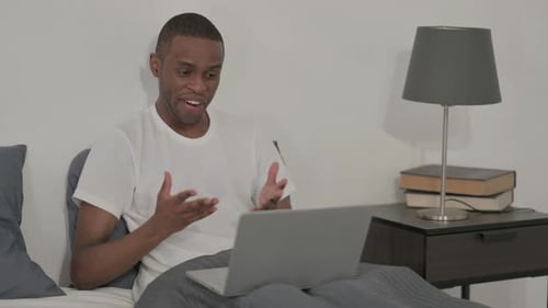 Man Using Laptop in Bed for Video Call