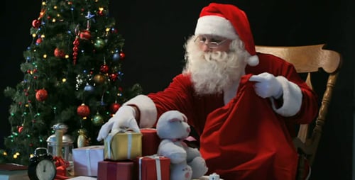 Santa Packing Gifts into Red Christmas Bag