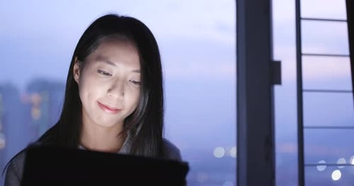 Woman Using Tablet Computer at Night in City Apartment
