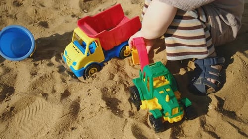 Child Playing with Toy Trucks in Sand