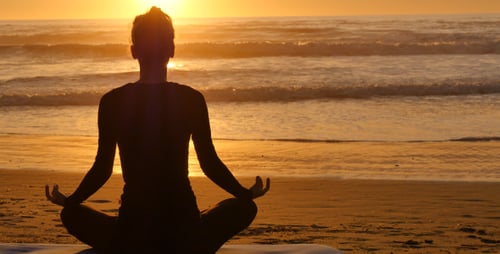 Woman Meditating at Sunrise on Peaceful Beach