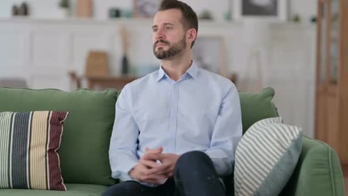 Bearded Man Sitting on Couch Gets Up