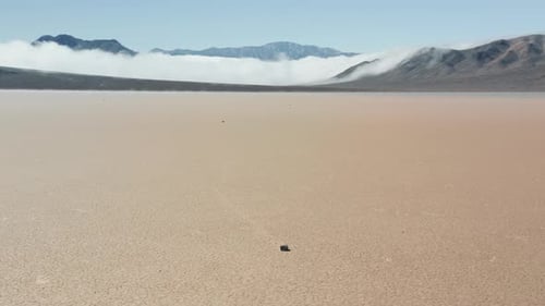 Cinematic Aerial of Moving Stones By Smooth Cracked Surface of Desert,