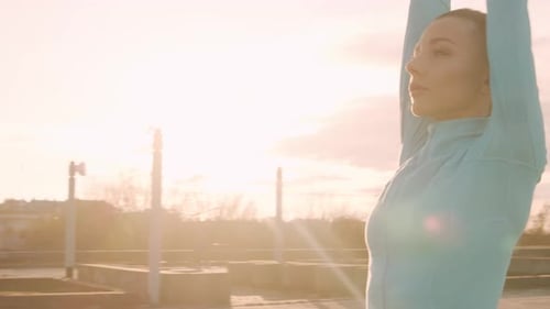 Woman Stretching on Rooftop During Golden Hour