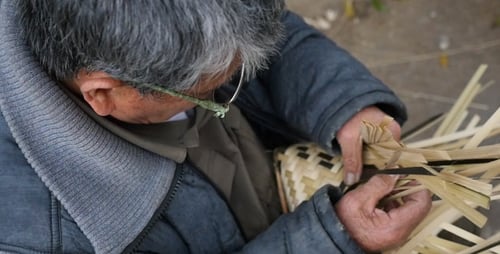 Großvater macht mit einem maschinell gewebten Bambus