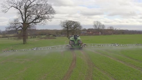 Tractor Sprays Large Green Agricultural Field