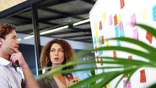 Businesspeople discussing over sticky notes