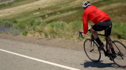 A man road biking on a scenic road.