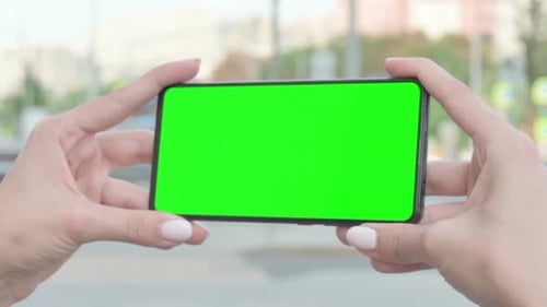 Close Up of Female Hand Holding Smartphone with Green Screen Outdoor