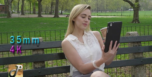 Woman with Tablet Relaxing in Park on Bench